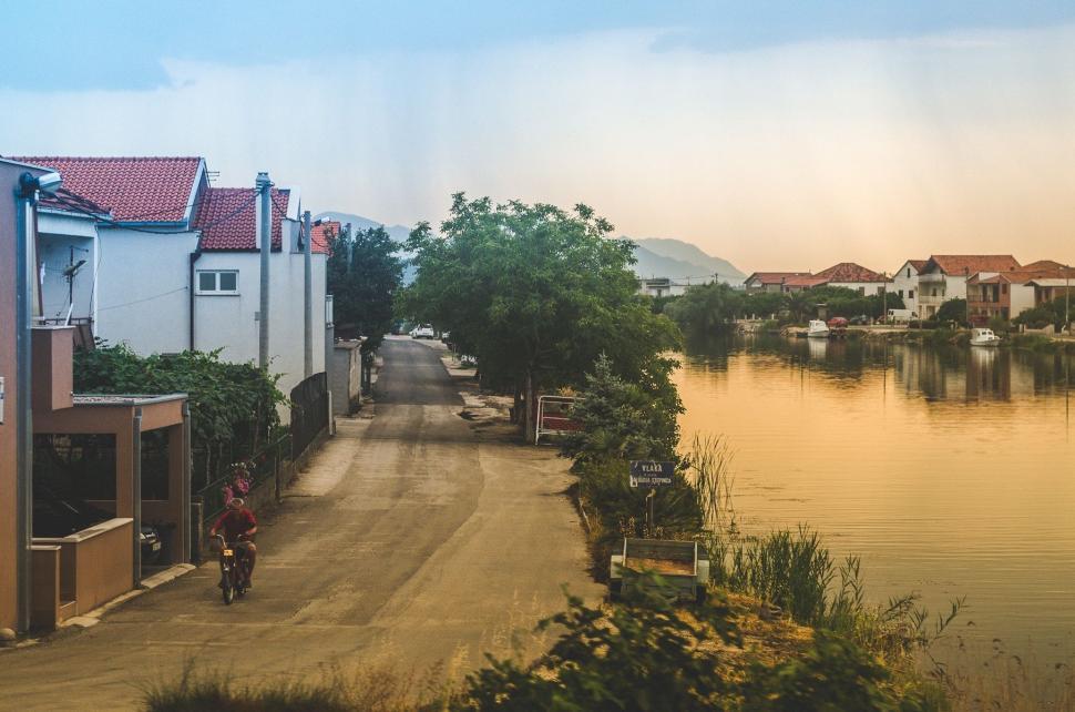 Free Image of Man Riding Motorcycle Down Street Next to River 