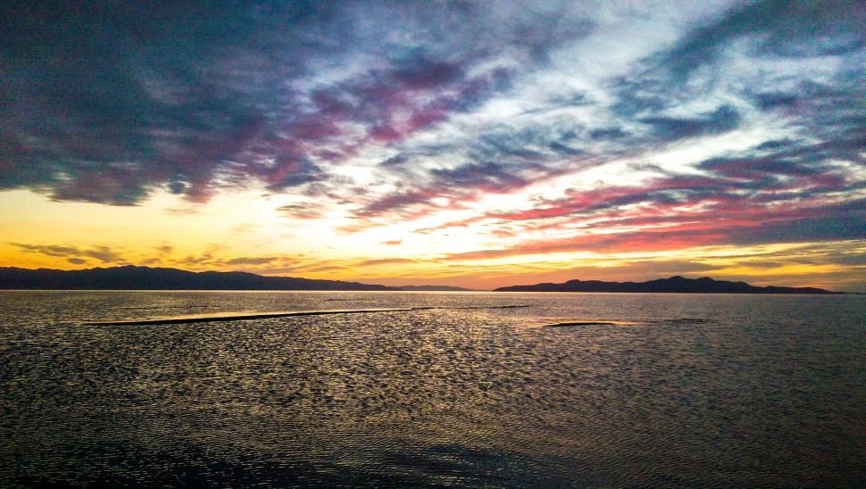 Free Image of Sun Setting Over Ocean With Small Island 