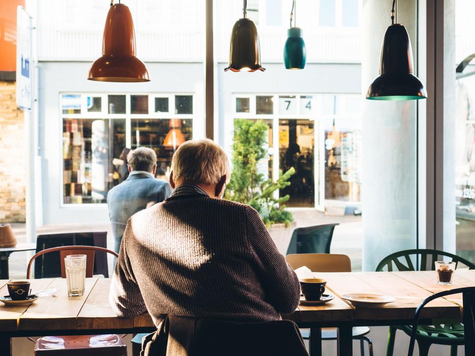 Free Image of Man Sitting at Table Looking Out Window 