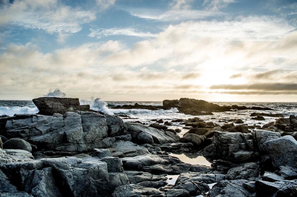 Free Image of Person Standing on Rocky Beach With Surfboard 