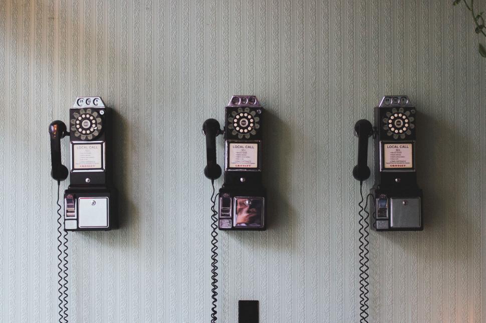 Free Image of Row of Old Fashioned Telephones Mounted to a Wall 