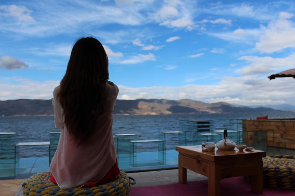 Free Image of Woman Sitting on Bench Looking Out at Water 