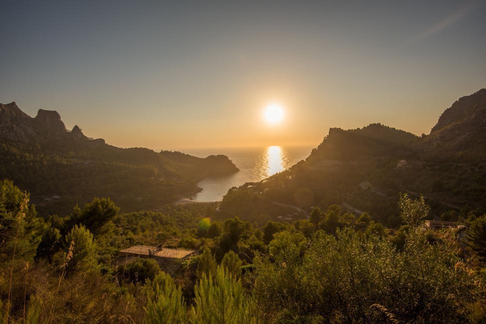 Free Image of Sun Setting Over Mountains and Water 