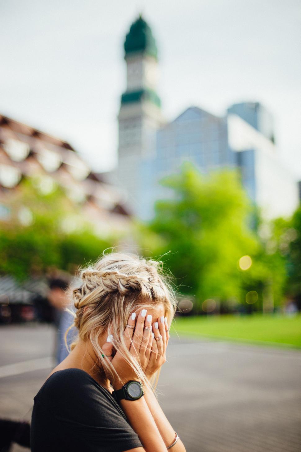 Free Image of Woman Sitting on Park Bench Covering Face With Hands 