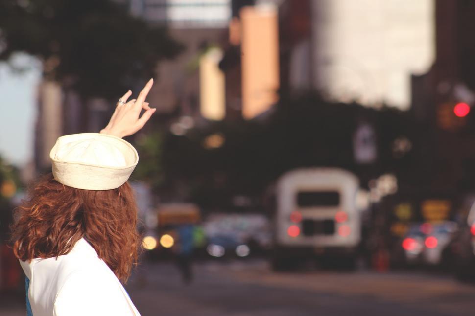 Free Image of Woman in White Dress and Hat Walking Down Street 