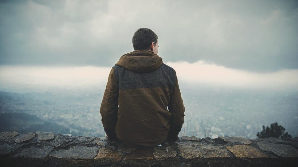 Free Image of Man Sitting on Top of Stone Wall 