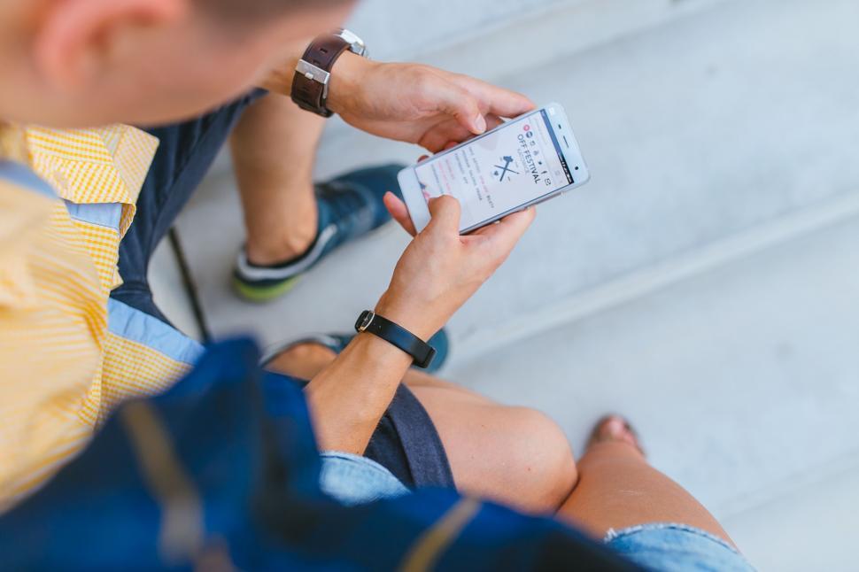 Free Image of Man Sitting on Steps Looking at Cell Phone 