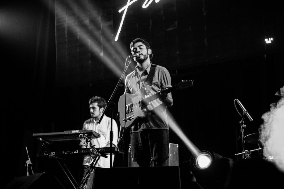 Free Image of Man Standing on Stage Holding Guitar 