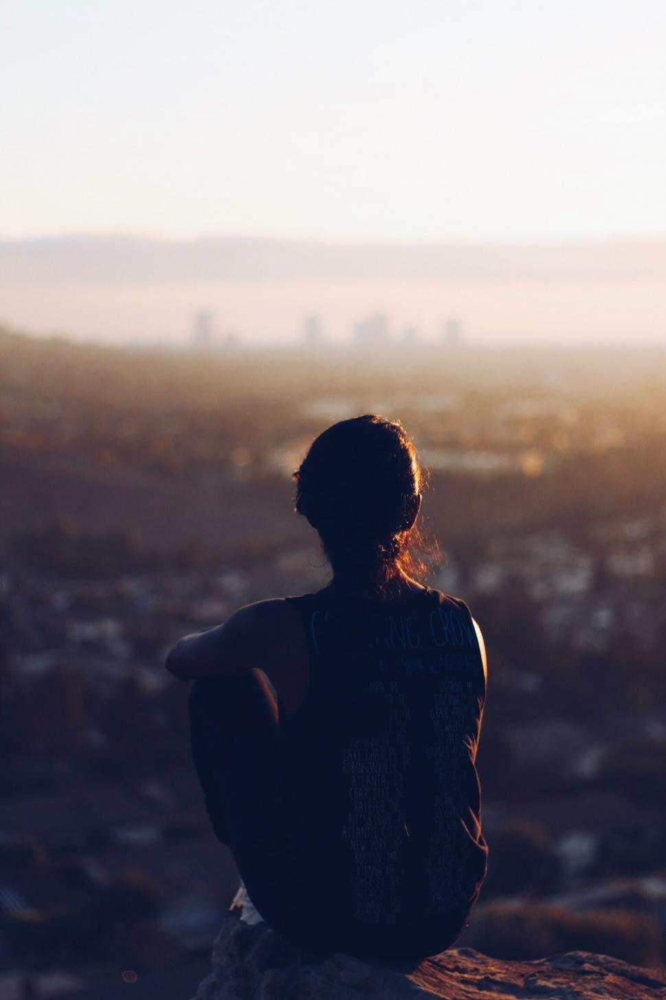Free Image of Person Sitting on Rock Overlooking City 