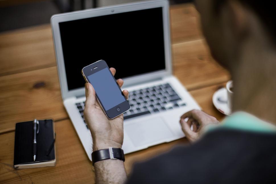 Free Image of Man Sitting at Table Using Cell Phone 