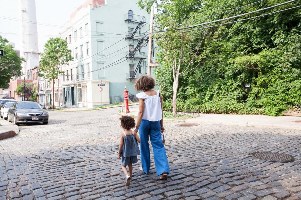 Free Image of Woman and Little Girl Walking Down Street 