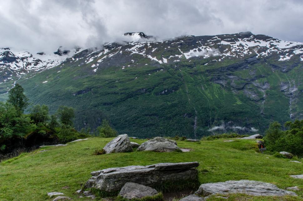 Free Image of Grassy Field With Rocks and Mountain 