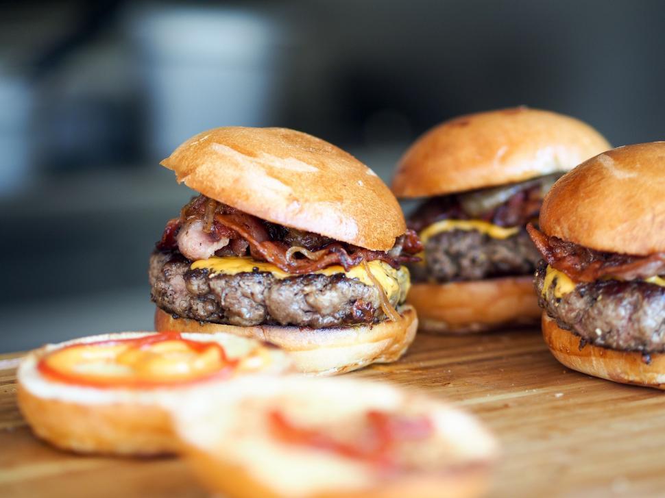 Free Image of Three Hamburgers on Wooden Cutting Board 