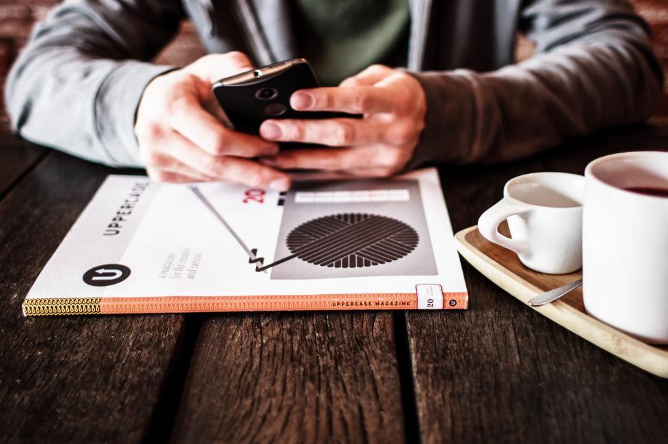 Free Image of Man Sitting at Table Using Cell Phone 