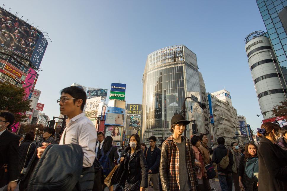 Free Image of Group of People Walking Down Street Next to Tall Buildings 