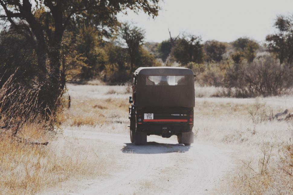 Free Image of Truck Driving Down Dirt Road in Field 