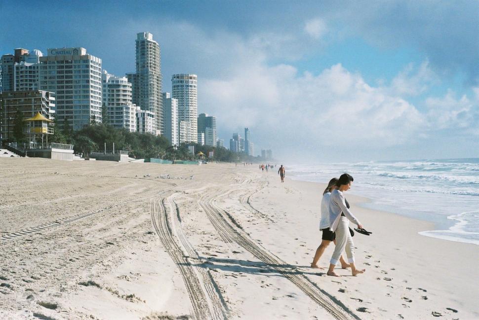 Free Image of Two People Walking on a Beach Near the Ocean 