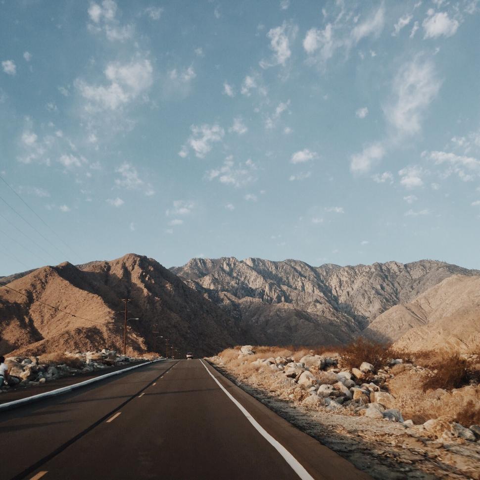 Free Image of Car Driving Down Road With Mountains in Background 