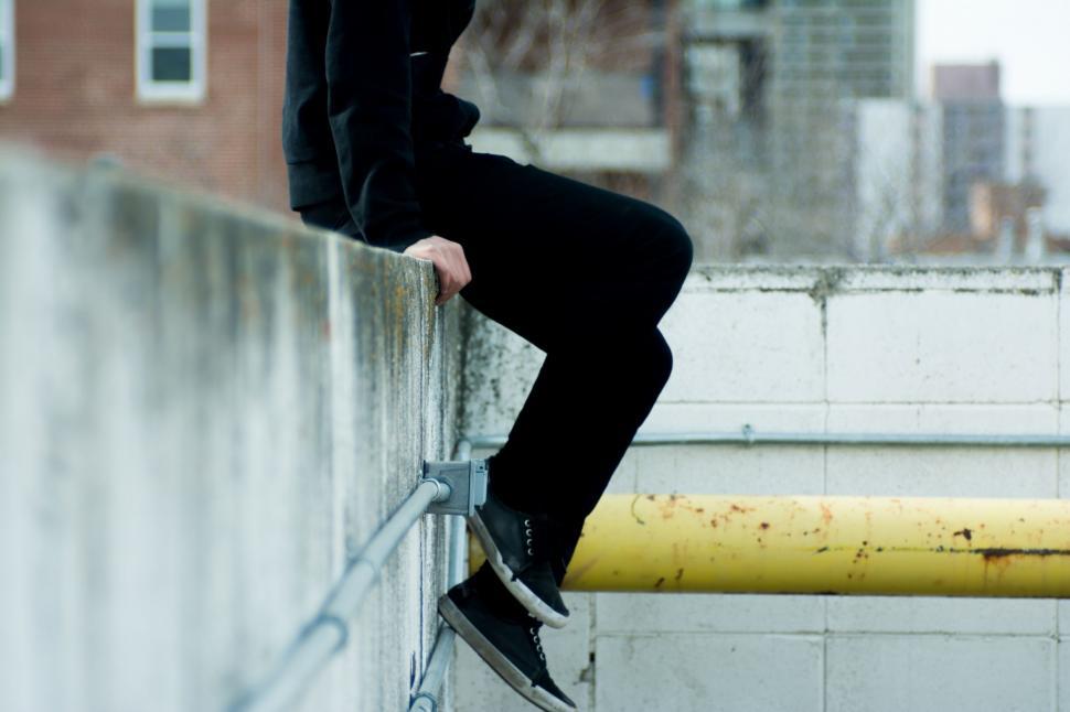 Free Image of Man Sitting on Ledge With Feet on Rail 