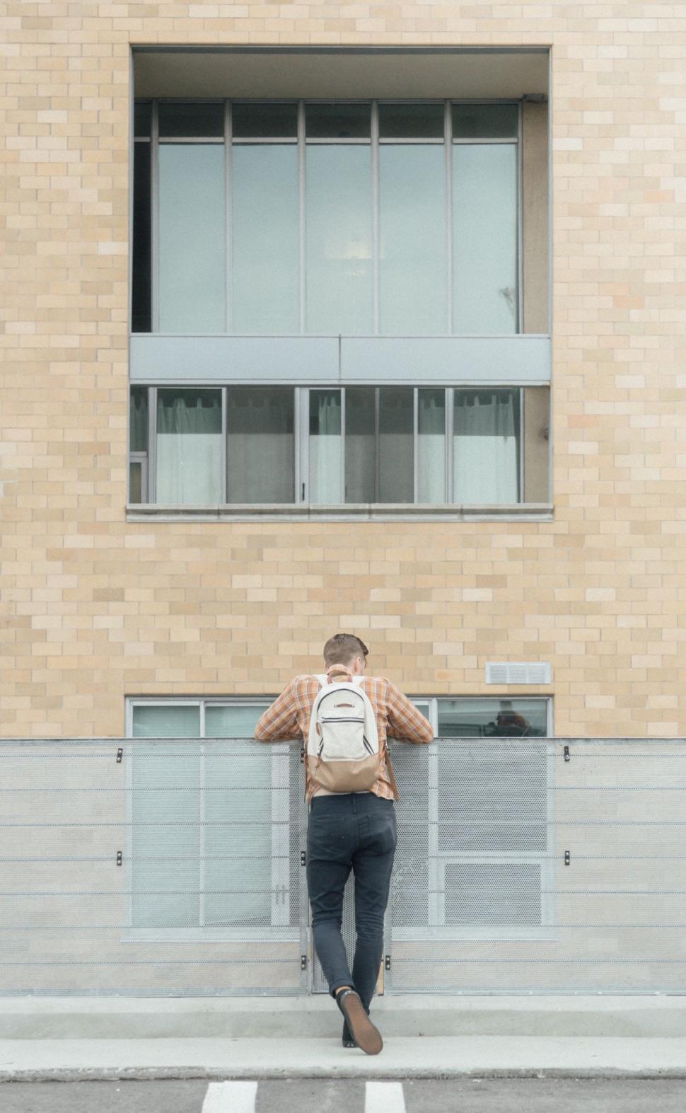 Free Image of Man Walking Down Street Next to Tall Building 