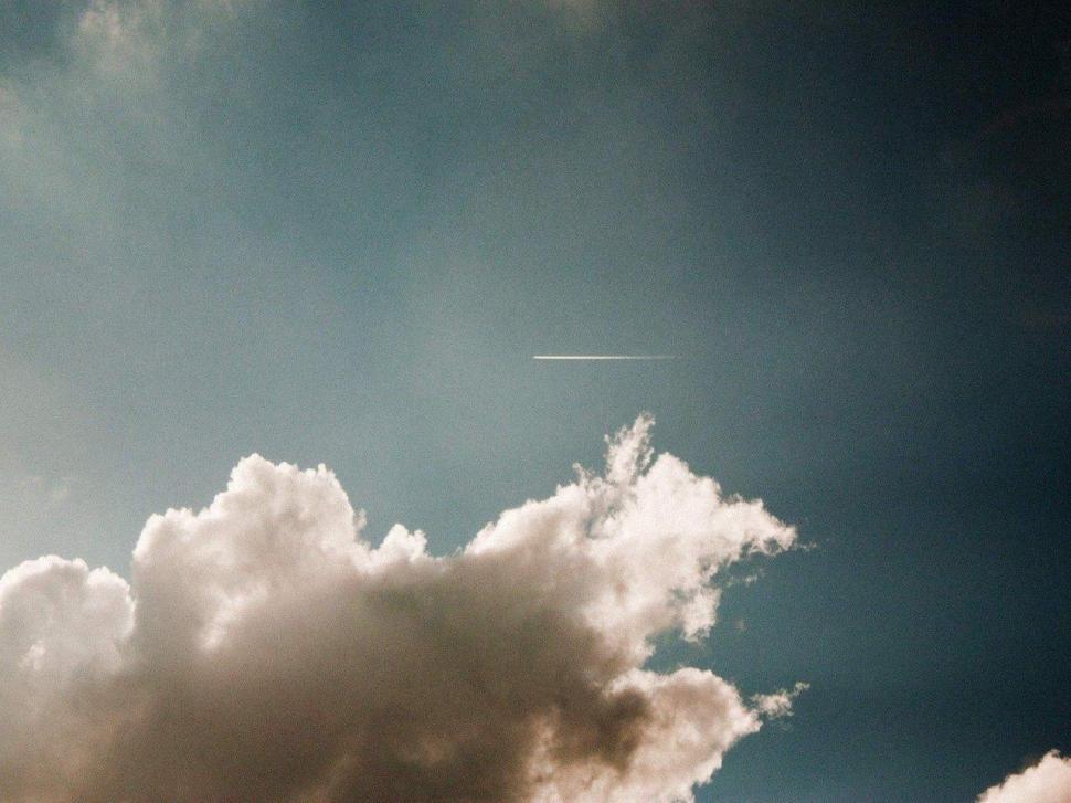 Free Image of Plane Flying Through Cloudy Blue Sky 
