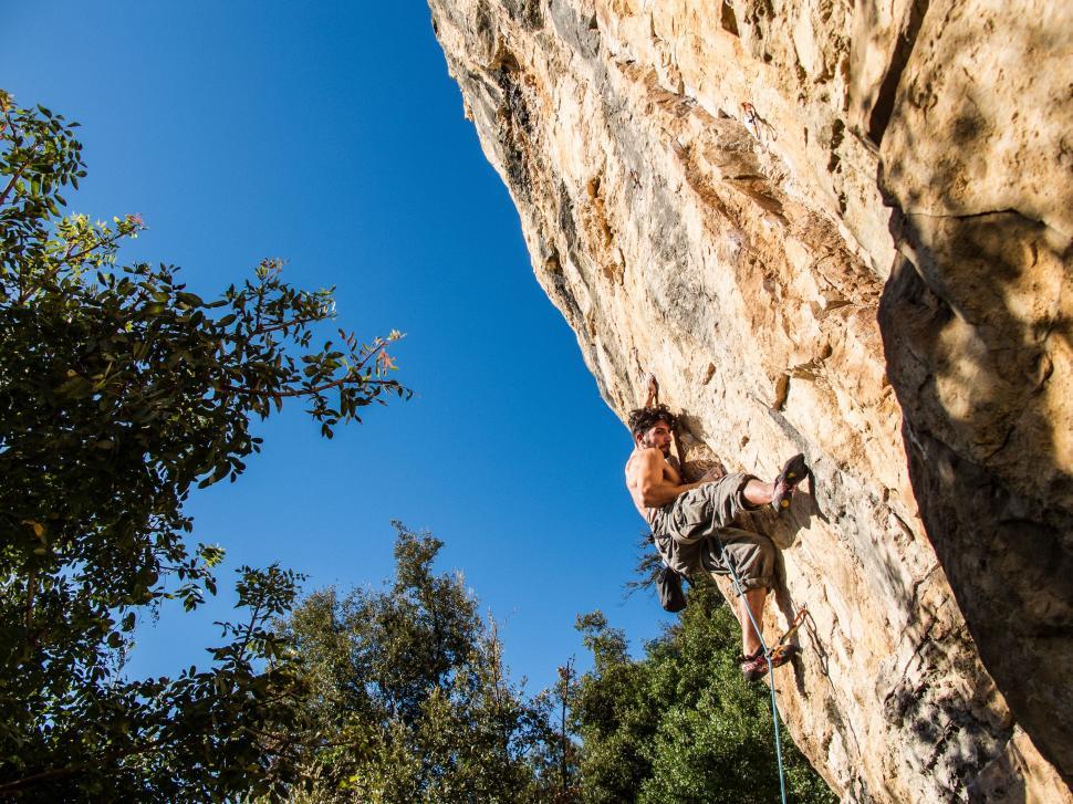 Free Image of Man Climbing Up Cliff Face 
