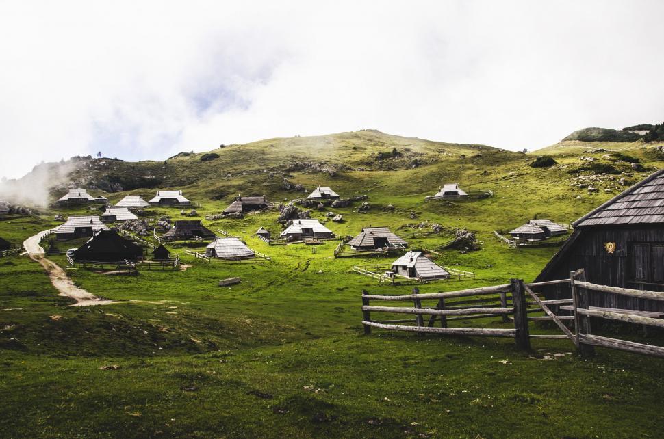 Free Image of Grassy Field With Wooden Fence and Buildings 