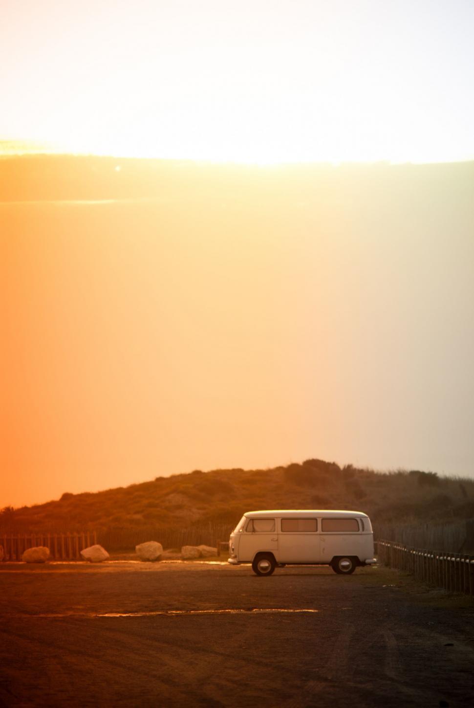 Free Image of White Van Driving Down Road Alongside Hill 