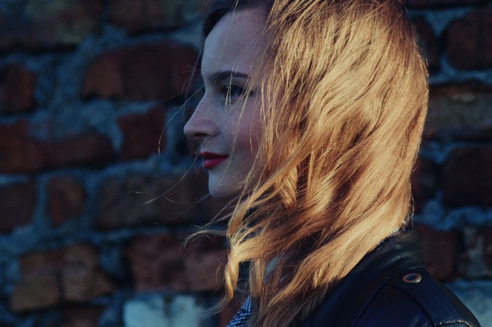Free Image of Woman With Long Hair Standing in Front of Brick Wall 