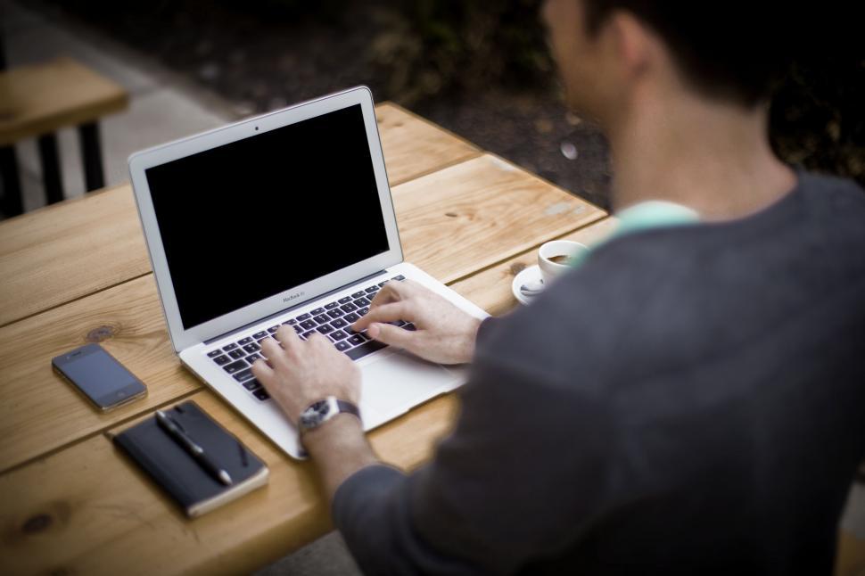 Free Image of Man Sitting at Table Using Laptop Computer 