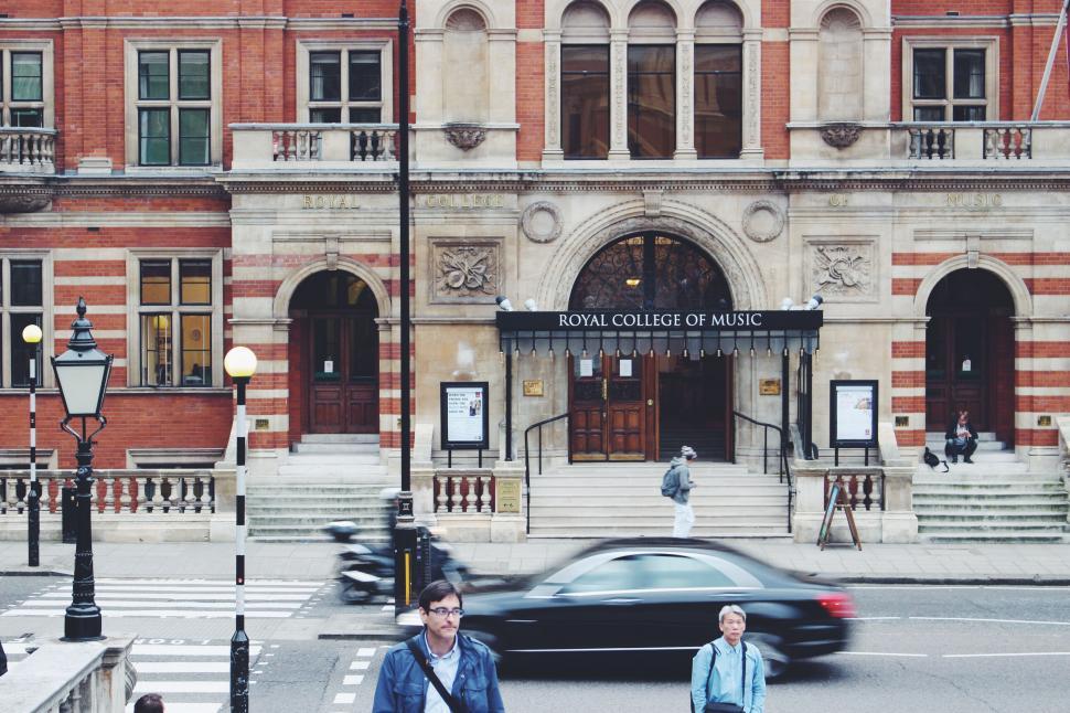 Free Image of Two People Crossing a Street in Front of a Building 
