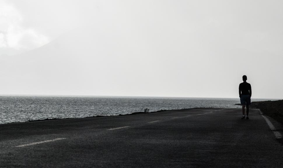 Free Image of Man Walking Along Ocean Road 