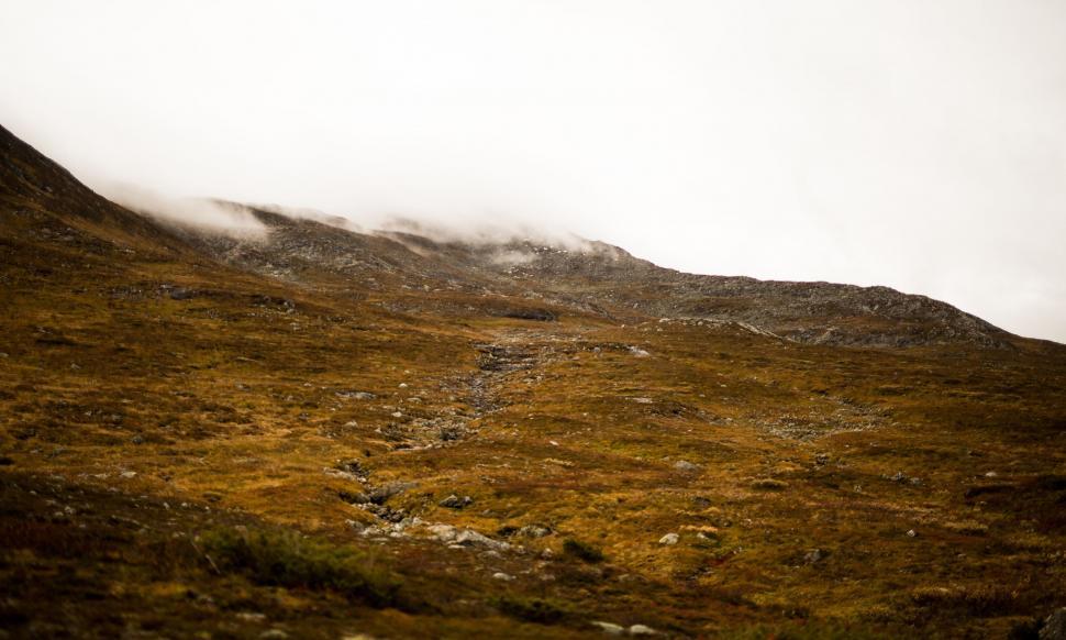 Free Image of Person Walking Up a Hill With Snowboard 