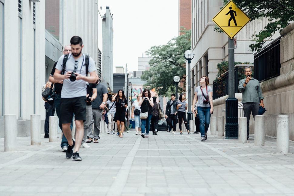 Free Image of Group of People Walking Down Street Next to Tall Buildings 