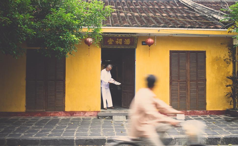 Free Image of Man Riding Bicycle Past Yellow Building 