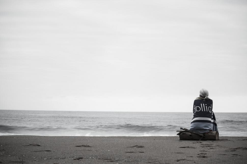 Free Image of Person Sitting on Top of Beach Next to Ocean 
