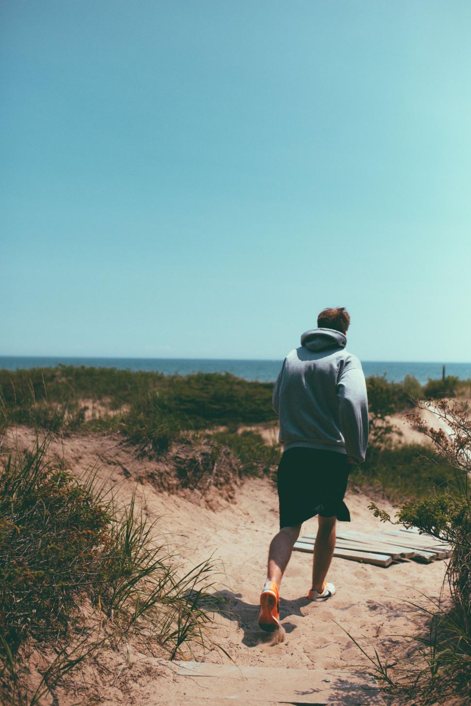 Free Image of Man Walking Down Path to Beach 
