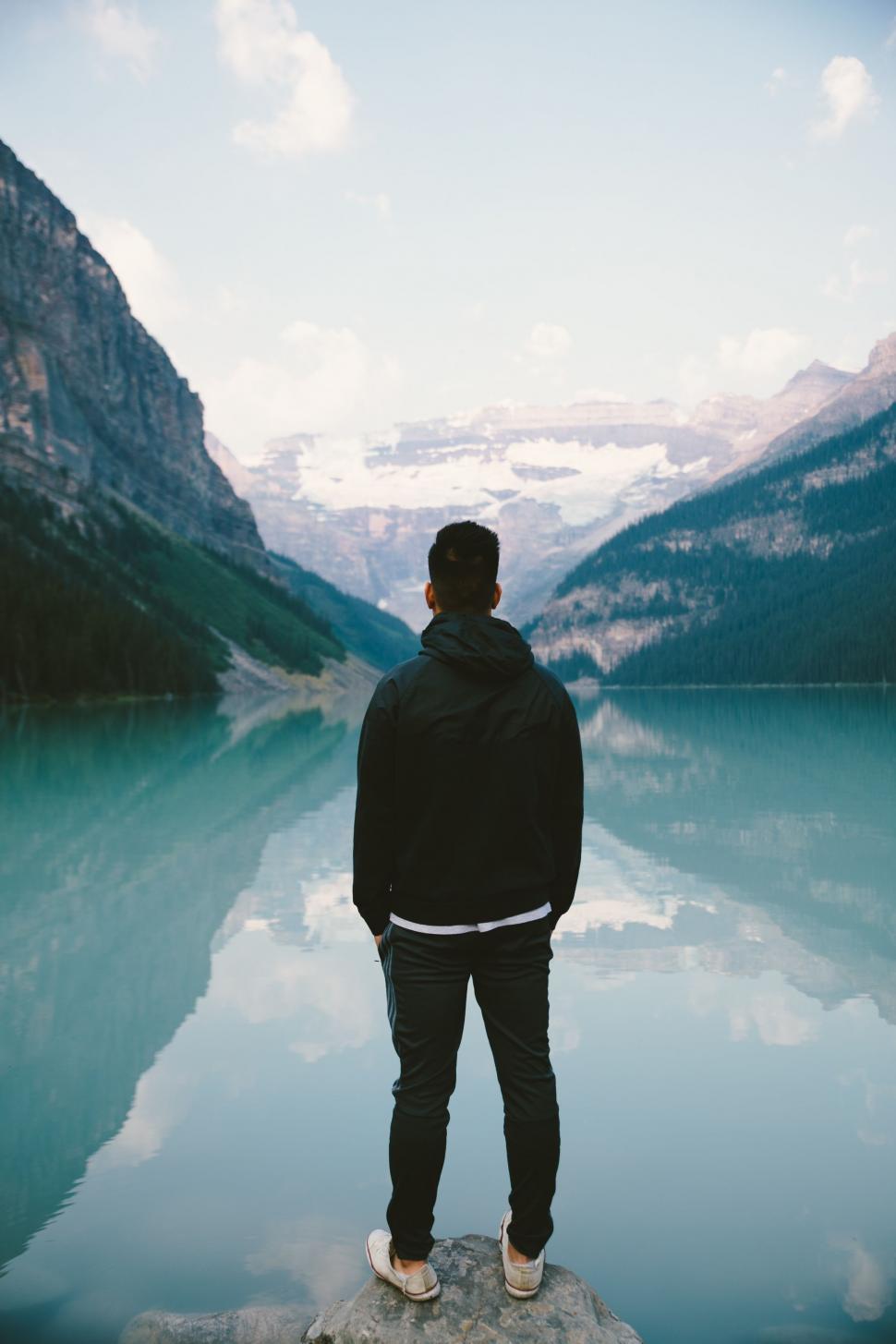 Free Image of Man Standing on Rock by Water 