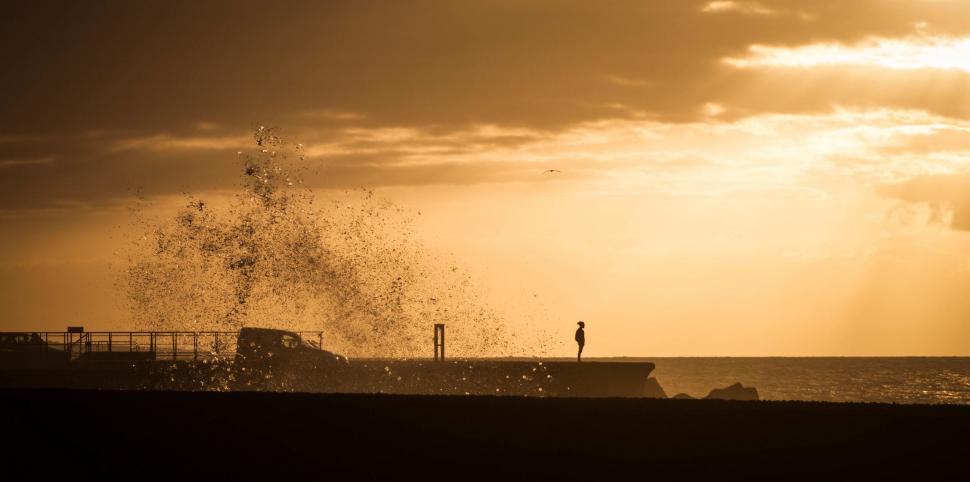 Free Image of Person Standing on Beach Next to Boat 
