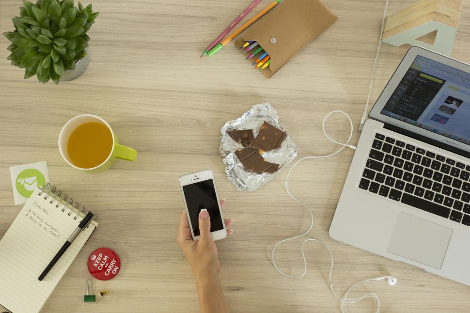 Free Image of Person Using Cell Phone Next to Laptop 