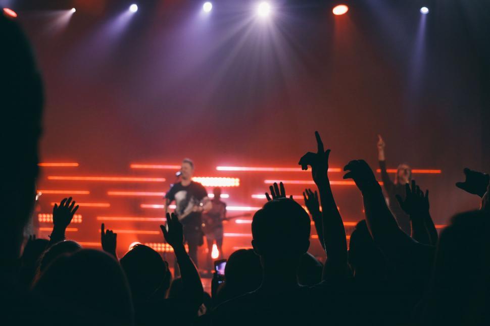 Free Image of Band Performing on Stage With Hands Raised in Air 
