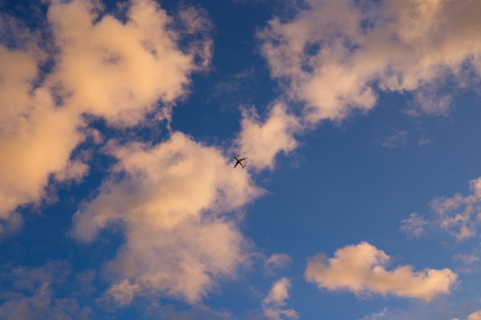 Free Image of Plane Flying Through Cloudy Blue Sky 