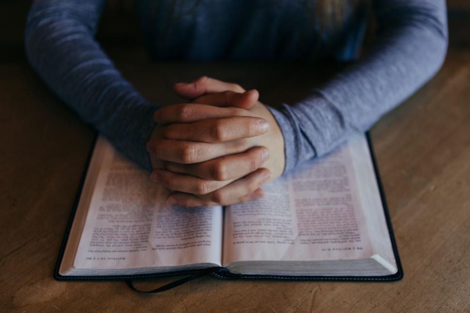 Free Image of Person Holding Hands Over a Book 