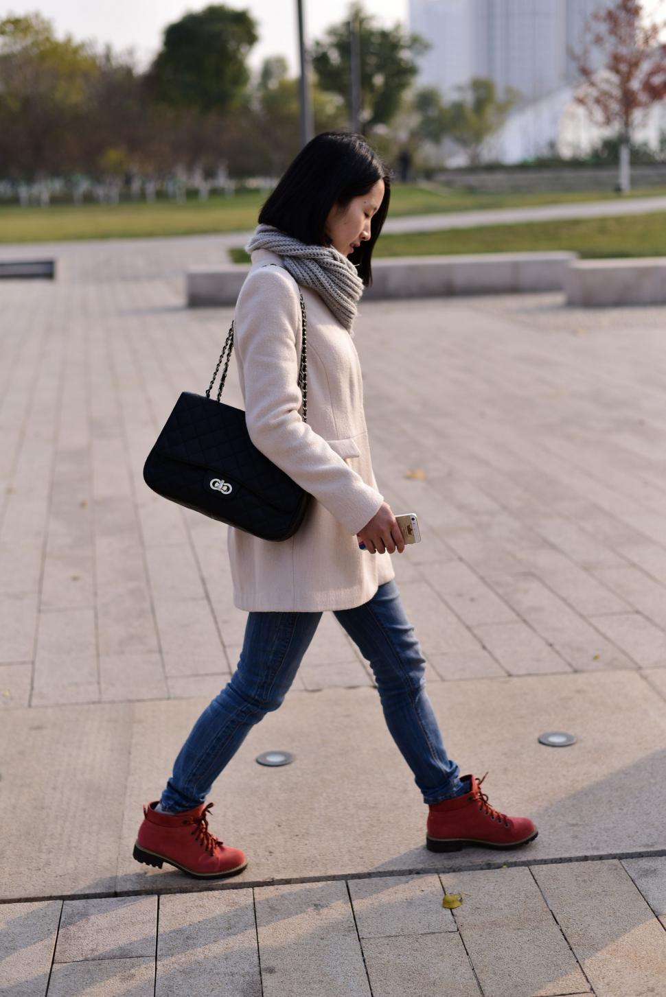 Free Image of Woman Walking Down Sidewalk With Black Bag 