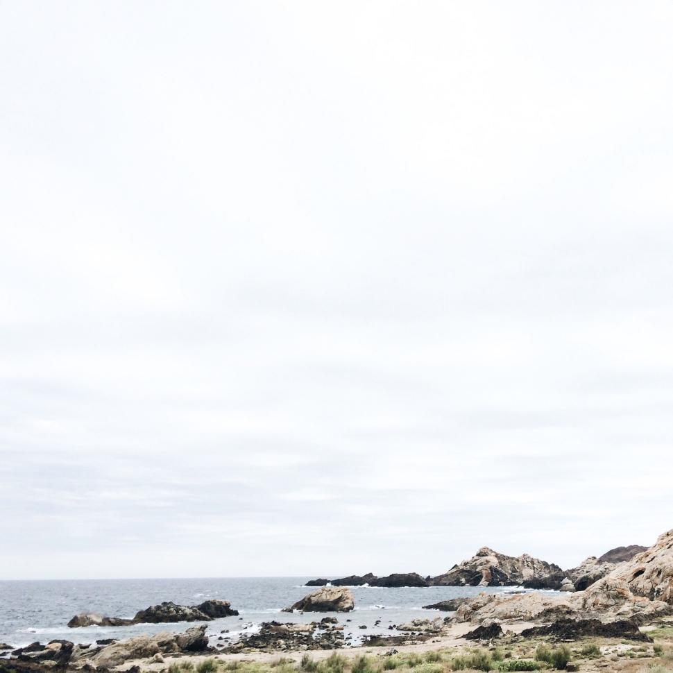 Free Image of Man Standing on Sandy Beach by the Ocean 