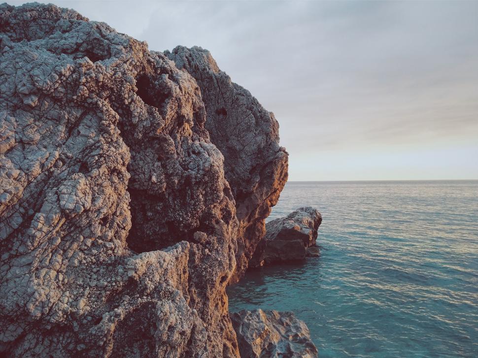 Free Image of Massive Rock Outcropping Extending Into Ocean 