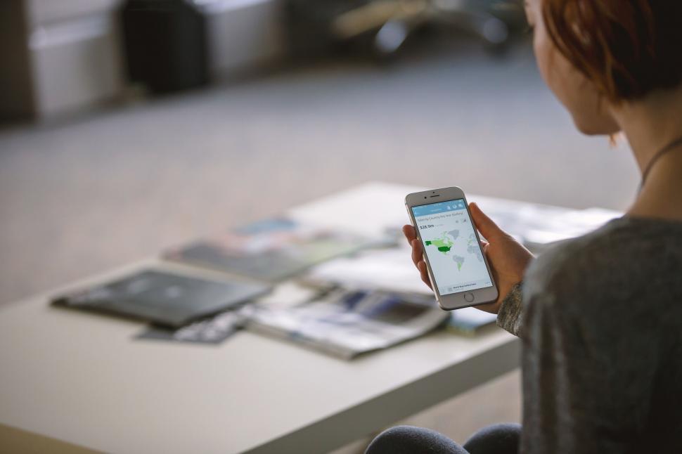 Free Image of Woman Sitting at Table Looking at Cell Phone 