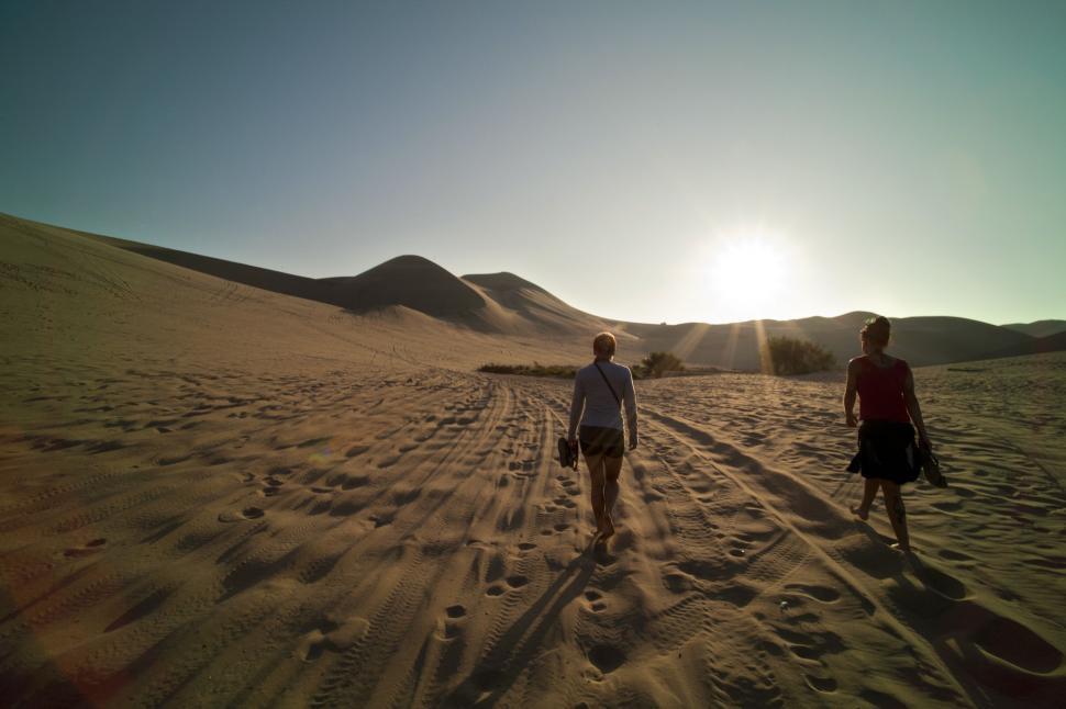 Free Image of Two People Walking in the Sand 