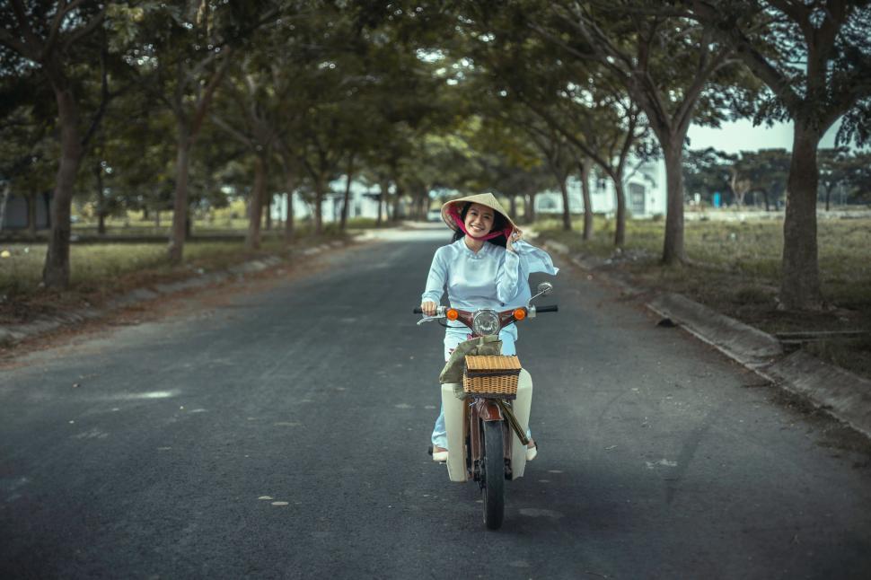 Free Image of Woman Riding Motorcycle Down Street 
