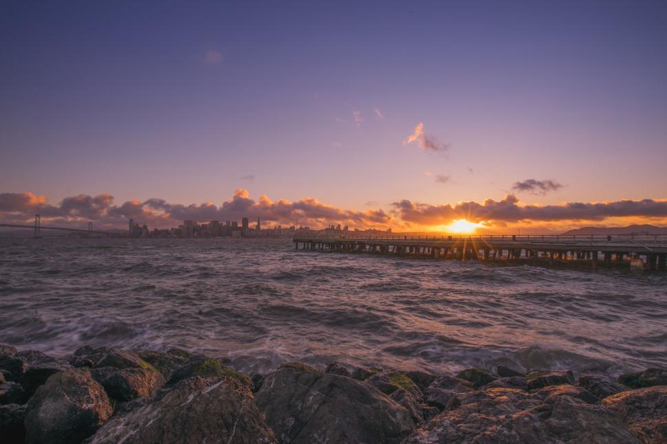 Free Image of Sunset Over Body of Water With Rocks in Foreground 